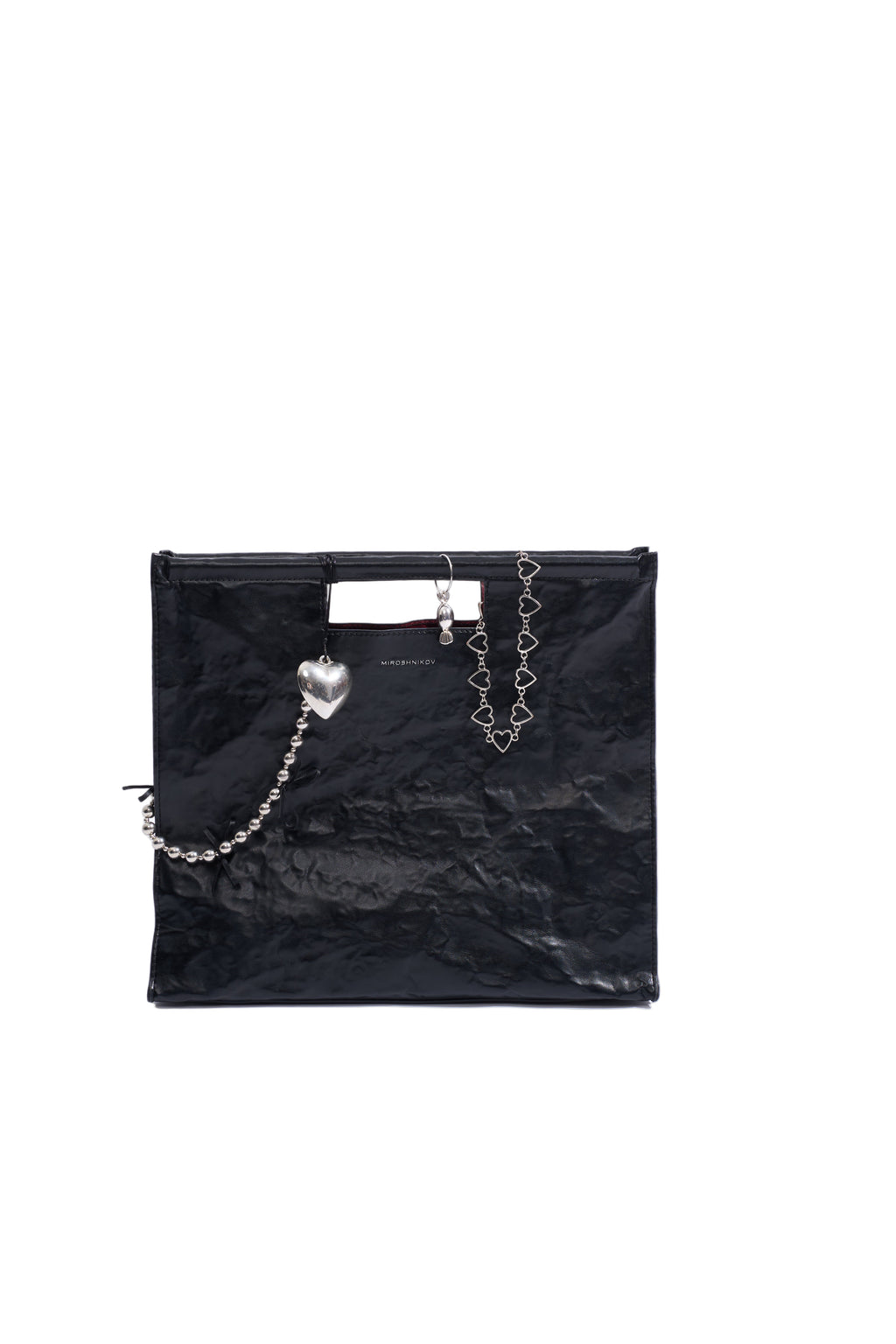 Black glossy handbag with decorative chains on a white background
