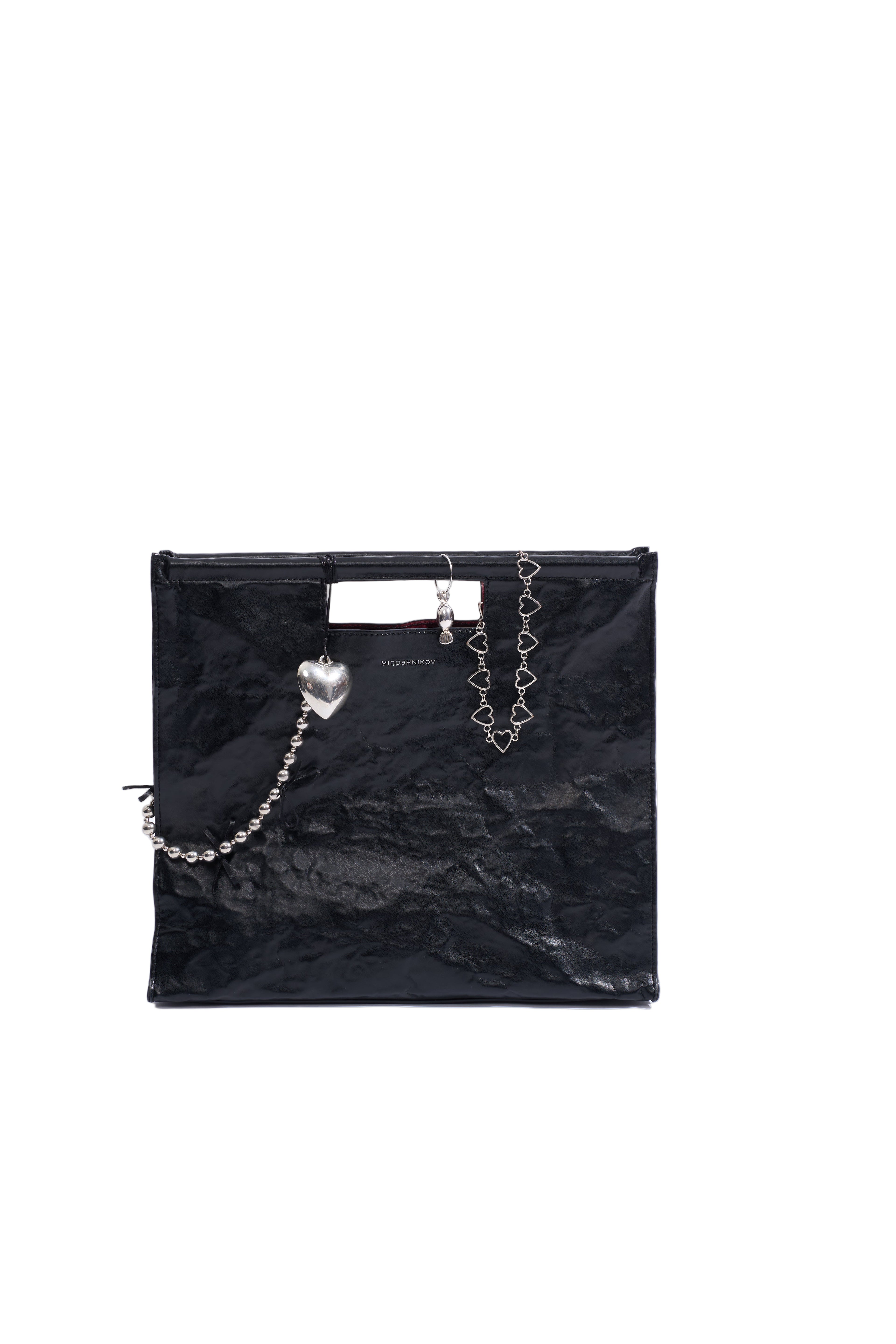 Black glossy handbag with decorative chains on a white background