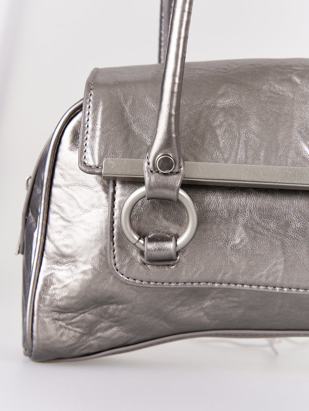 Silver metallic handbag with handle and clasp on a white background